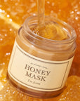 picture of poring honey on I'm from honey mask laying on honeycombs background