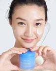 korean woman holding 70ml bottle of laneige water sleeping mask ex with mask on her face