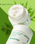 two containers of innisfree green tea seed hyluronic cream, one is open, on a two different shades of green background with leaves. vegan skincare