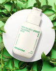 picture of innisfree green tea seed hyaluronic serum on a white platform with green tea leads on green background