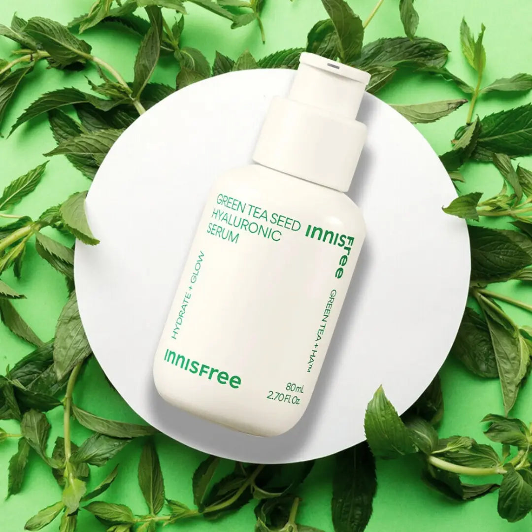 picture of innisfree green tea seed hyaluronic serum on a white platform with green tea leads on green background